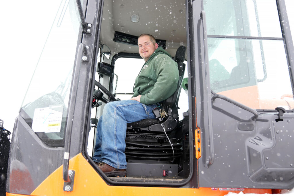 Smiling CVES staff member in the cab of a snow-removal loader