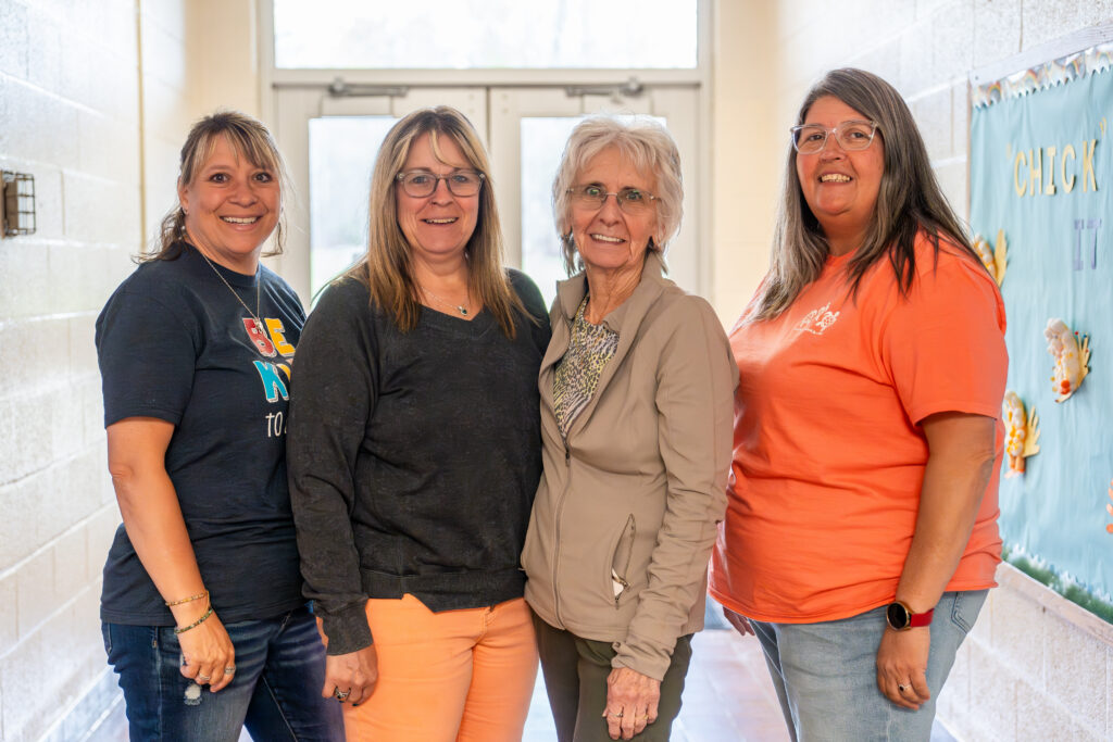 Four CVES staff members standing together in a school hallway