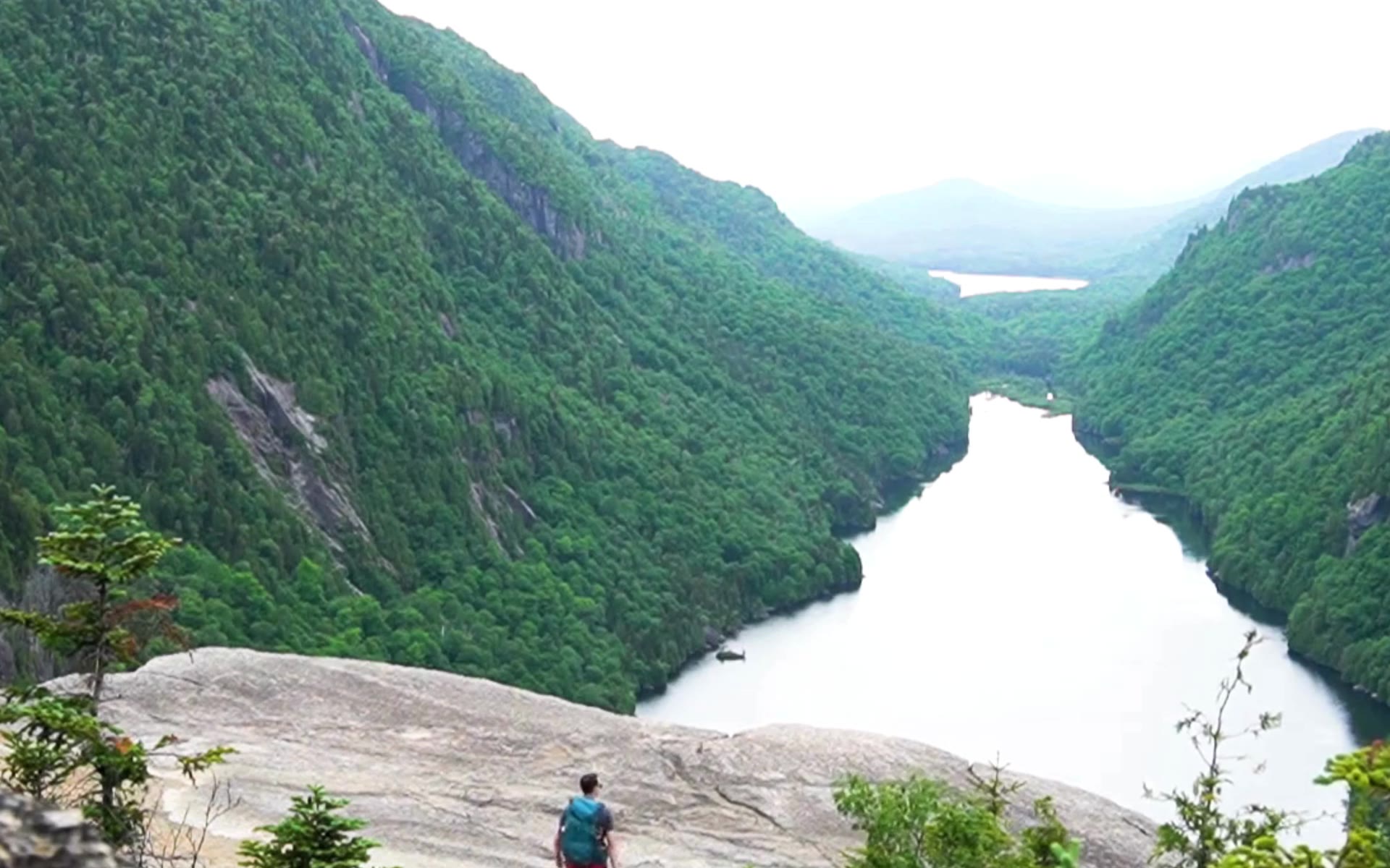Hiker overlooking a lake between steep mountain cliffs